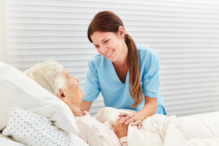Caring geriatric nurse cares for ill senior citizen in nursing home or hospice